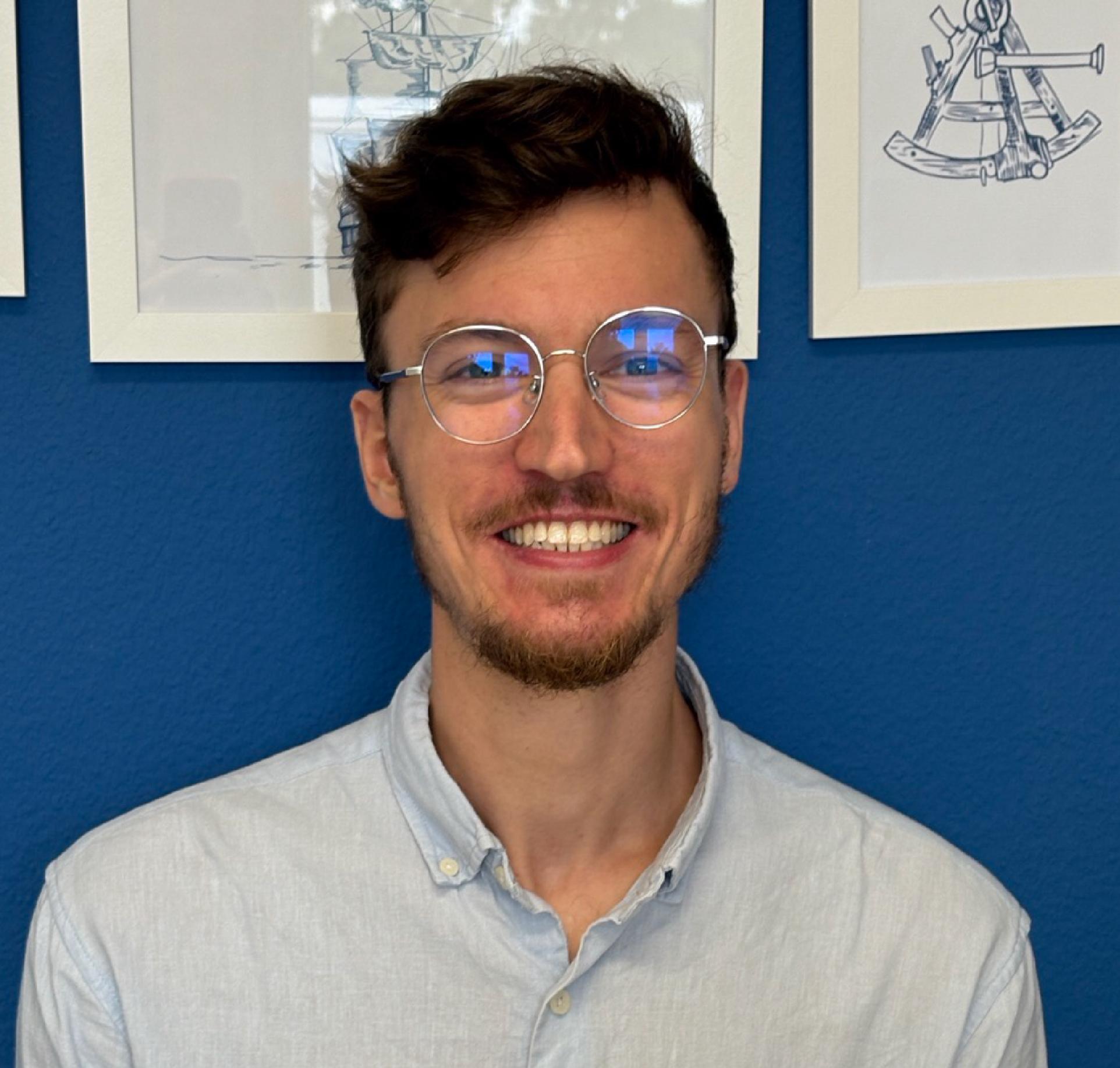 Fotografie einer lachenden Person vor einem blauen Hintergrund